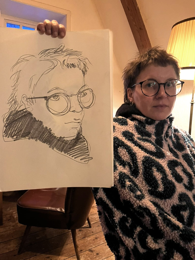 Eine Frau mit einer Portrait-Zeichnung von sich selber.