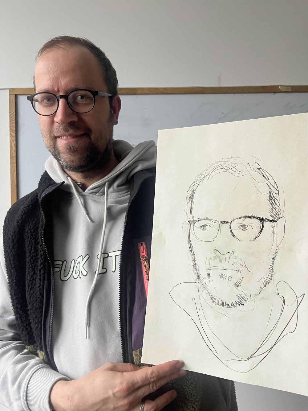 Ein Mann mit einer Portrait-Zeichnung von sich selber.