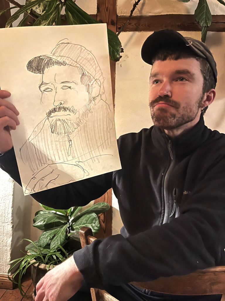 Ein Mann mit einer Portrait-Zeichnung von sich selber.